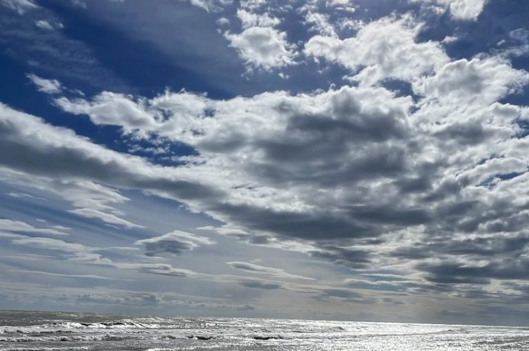 Weite der Natur Dramatischer Himmel über dem Ozean mit Wolken und spiegelndem Wasser.